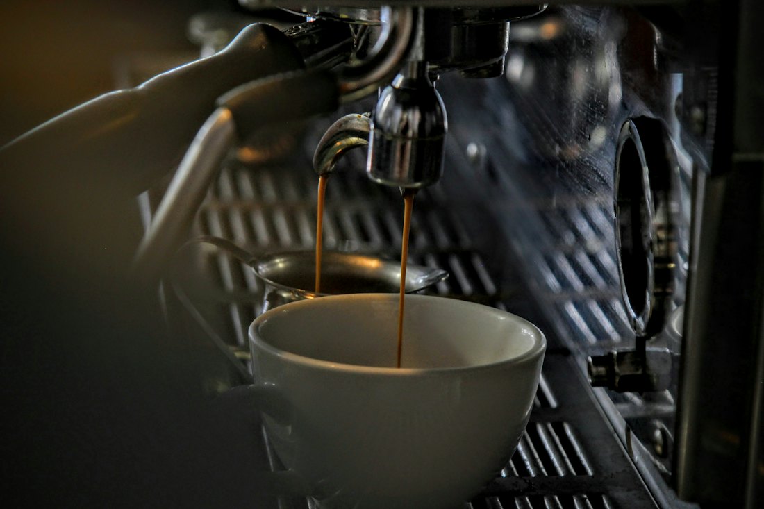 An espresso machine pouring coffee into a cup.