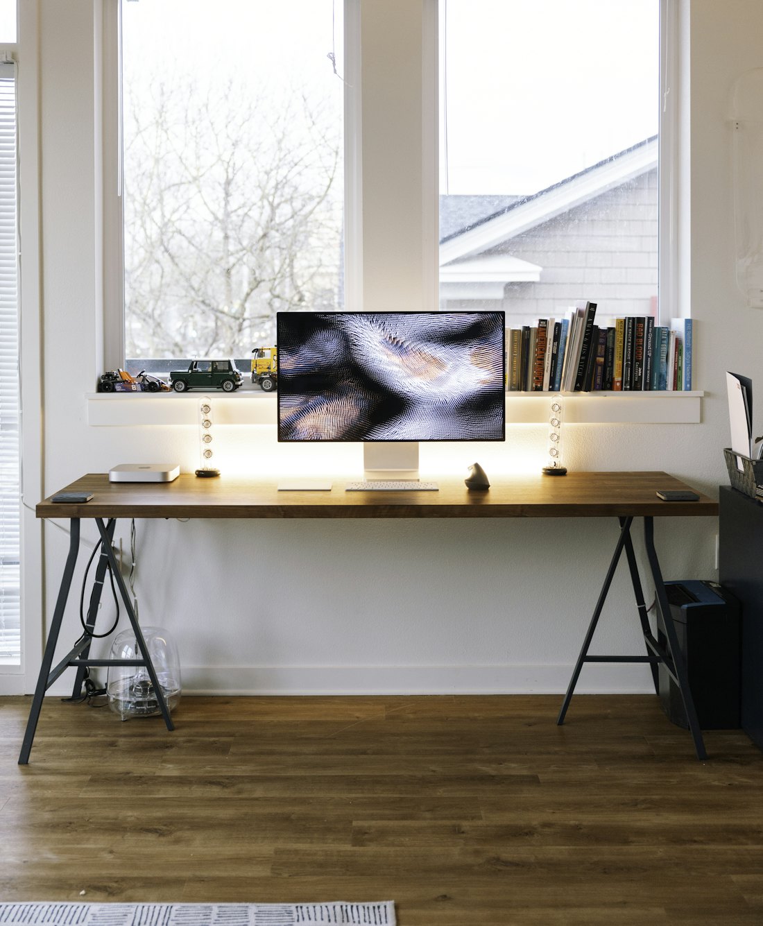 A home workspace by a window with a large display on a wooden desk.